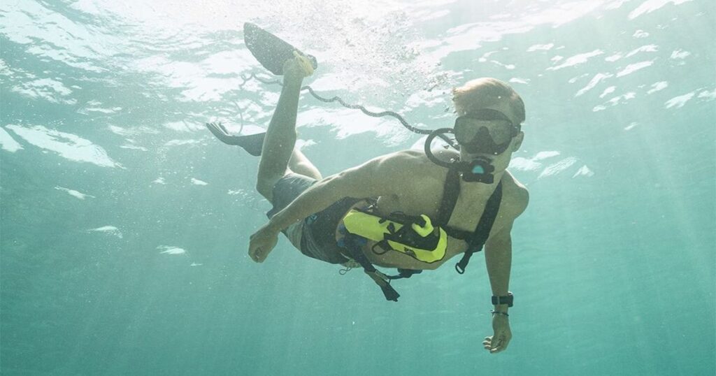 Guest from a charter yacht using a BLU3 Nomad Dive System in clear water