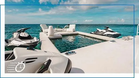 View of a FunSize Beach Club Sea Pool with inflatable deck area and jet skis in clear turquoise water