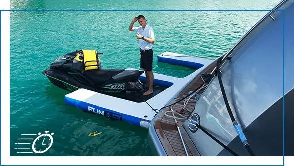 Crew member in white uniform standing on a FunAir blue inflatable jet ski dock with a jet ski alongside, turquoise water