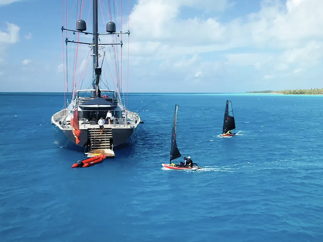 Tiwal Dinghies sailing near a yacht