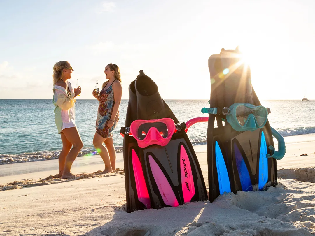 SCUBAPRO-fins-and-masks-on-beach-with-charter-gustes-in-the-background